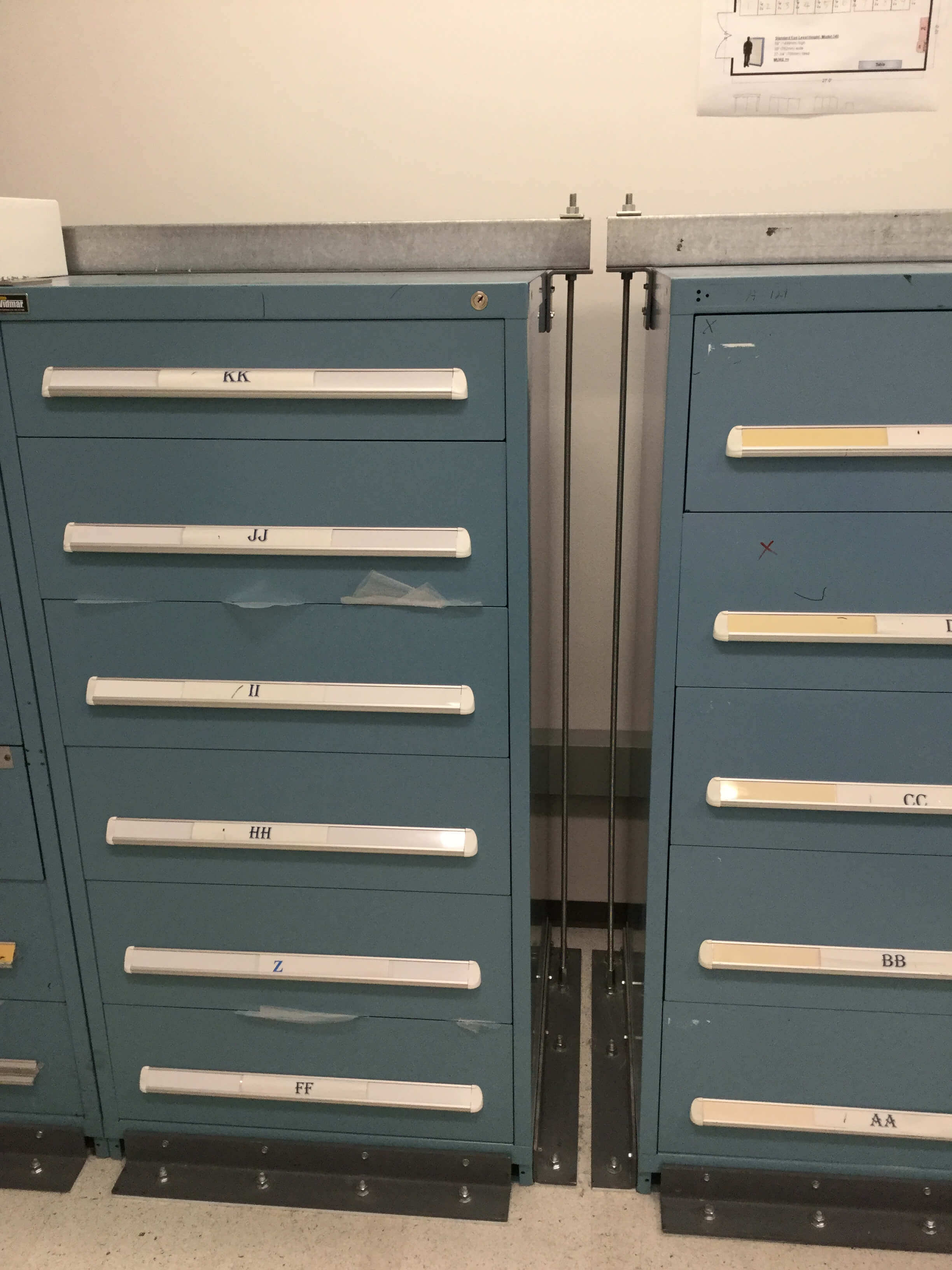 Welded bent steel plates bolted to the floor at the base of equipment cabinets